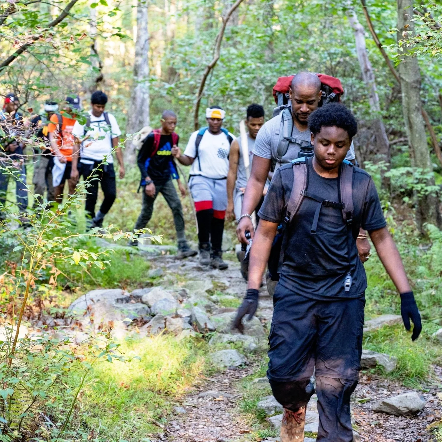 Camping to Connect participants hiking a wooded trail together